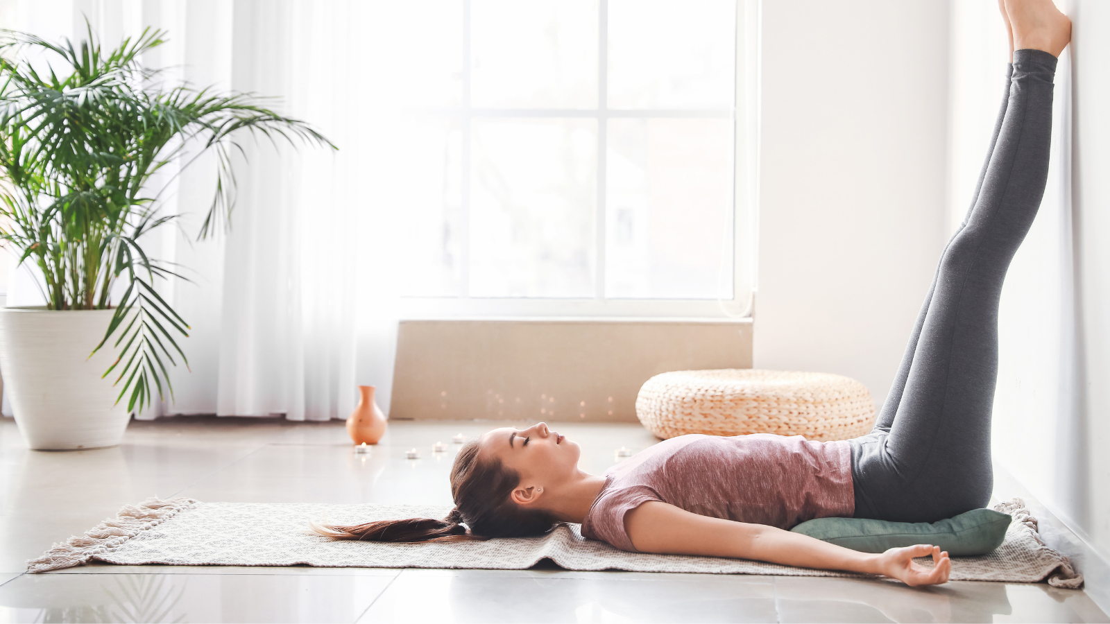 Beautiful young woman practicing yoga's Legs Up The Wall Pose at home.