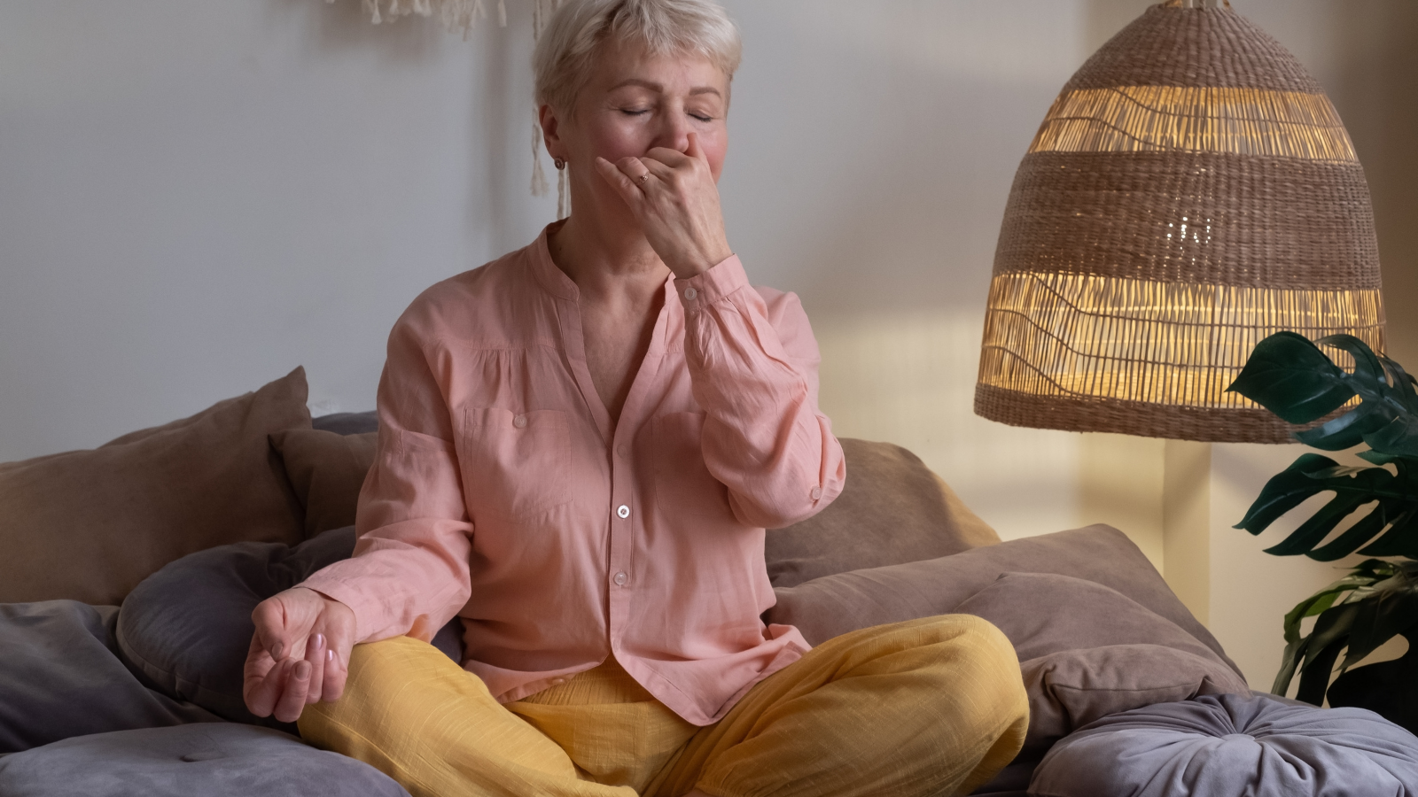 Senior woman practicing yoga at home, making Alternate Nostril Breathing exercise, nadi shodhana pranayama pose