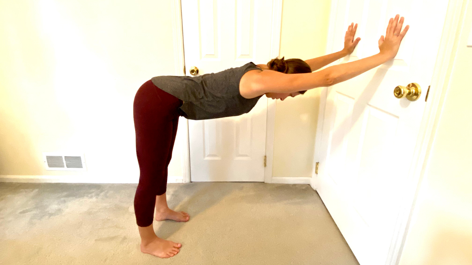 Practicing Downward Facing Dog Pose or Adho Mukha Svanasana at the Wall