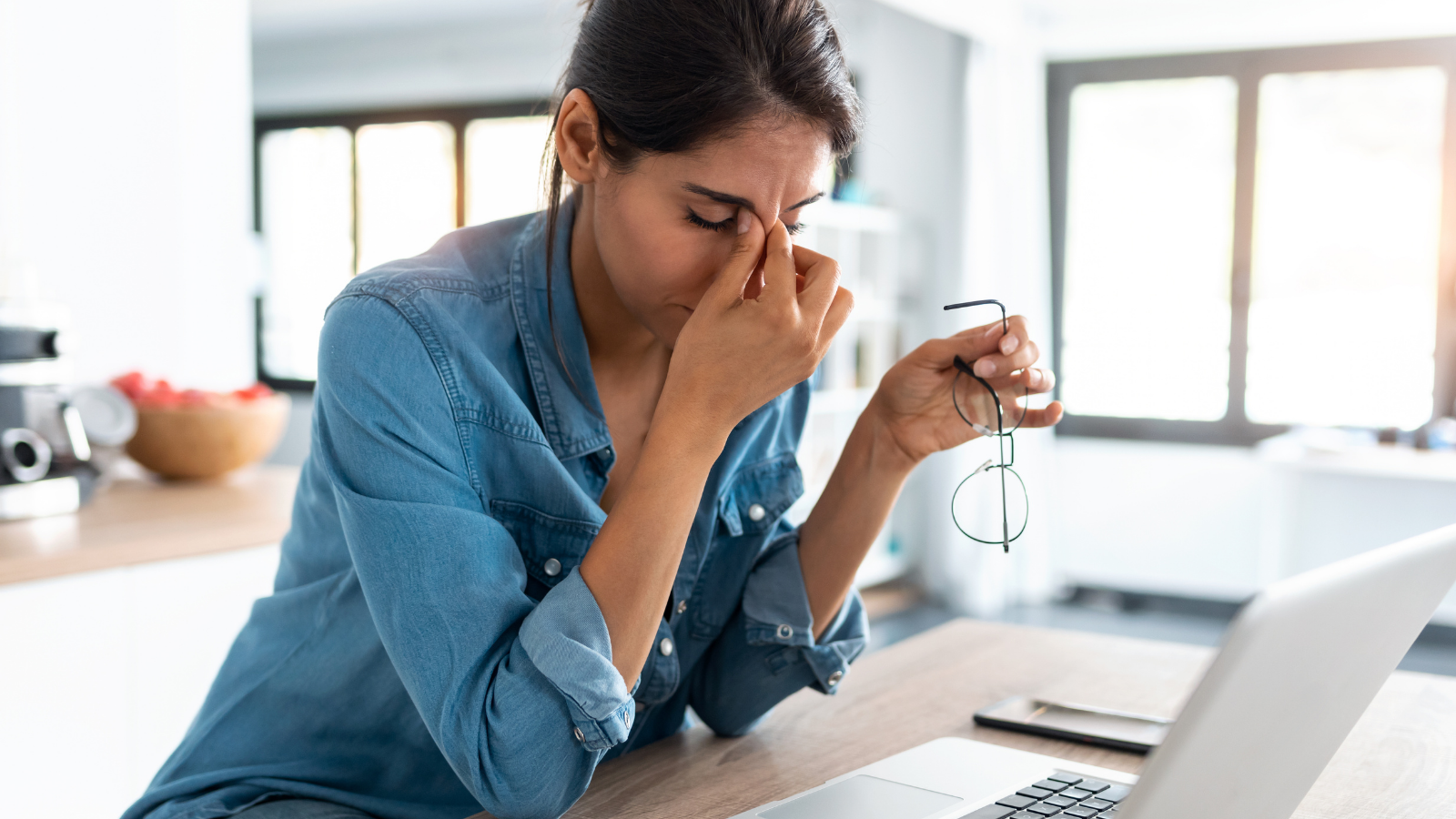 A stressed business woman working from home on laptop looking worried, tired and overwhelmed. 