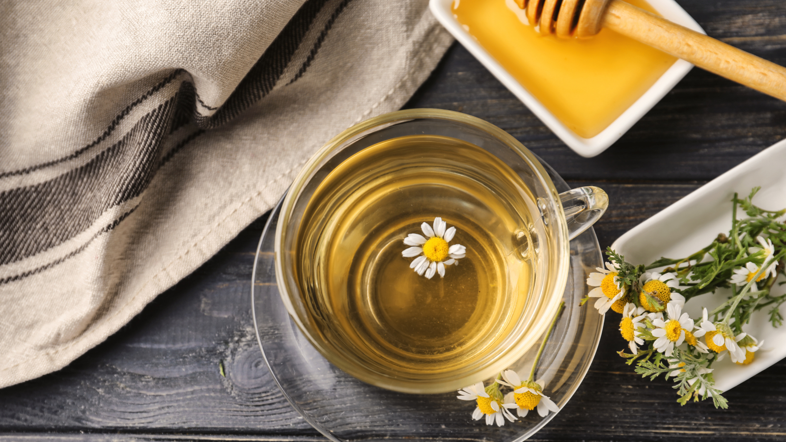 Cup of delicious camomile tea and honey on wooden table to sleep with no nighttime light